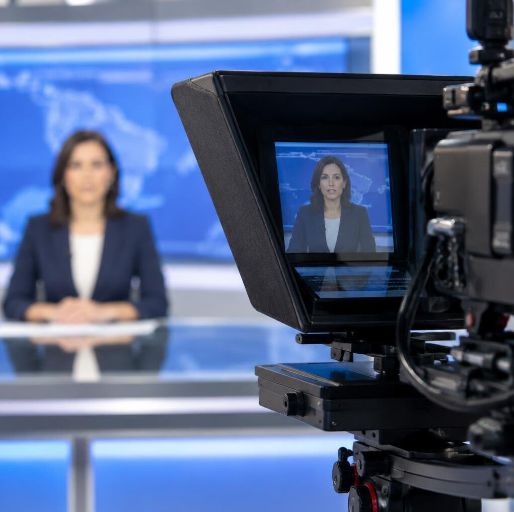 Close-up of a teleprompter with a presenter blurred in the background